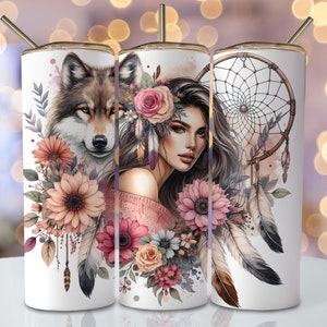 Pode incluir: Três copos de aço inoxidável com designs diferentes. O primeiro copo apresenta um lobo com detalhes florais. O segundo copo apresenta uma mulher com cabelo comprido e escuro usando uma coroa de flores e um suéter rosa. O terceiro copo apresenta um apanhador de sonhos com penas e detalhes florais.