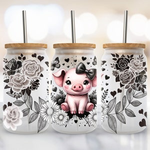 Può includere: Tre bicchieri di vetro con coperchi in legno e cannucce in metallo. Ogni bicchiere presenta un design diverso: uno con un motivo floreale bianco e nero, uno con un maiale rosa con un fiocco nero e l'ultimo con un motivo floreale bianco e nero.