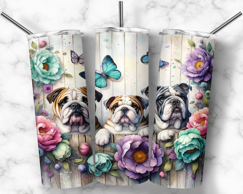 Op de afbeelding: Drie roestvrijstalen bekers met een bloemenontwerp en een bulldog die achter de bloemen uitkijkt. De bloemen zijn in tinten roze, paars, blauw en groen. Vlinders vliegen rond de bloemen.
