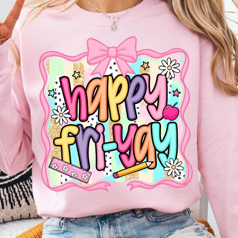 May include: Pink sweatshirt with a colorful graphic that says "Happy Fri-Yay." The design includes a pink bow, stars, daisies, an apple, a ruler, and a pencil. The background has gold glitter and pastel stripes.