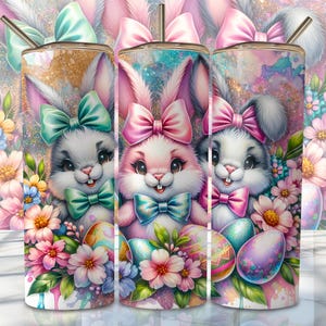 May include: Three stainless steel tumblers with a pink, white, and blue bunny rabbit design. The bunnies are wearing bows and holding Easter eggs. The background is a glittery pink and white with flowers.