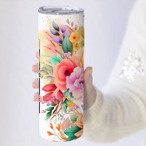 May include: A white stainless steel tumbler with a floral design. The design features pink, orange, yellow, and green watercolor flowers.