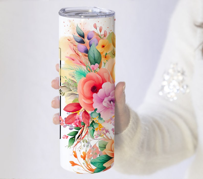 May include: A white stainless steel tumbler with a floral design. The design features pink, orange, yellow, and green watercolor flowers.