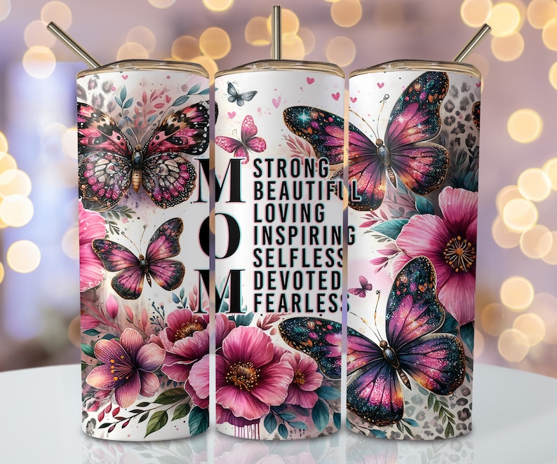 May include: A white tumbler with a floral design and butterflies. The tumbler has the word "MOM" in black letters and the words "Strong, Beautiful, Loving, Inspiring, Selfless, Devoted, Fearless" in black letters.
