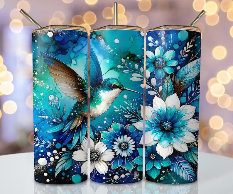 May include: Three stainless steel tumblers with a blue hummingbird and floral design. The hummingbird is flying over blue and white flowers with green leaves. The background is a blue and white watercolor effect.