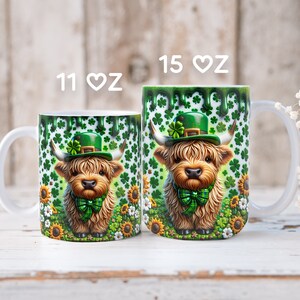May include: Two white ceramic mugs with a green shamrock and sunflower design. The mugs feature a cartoon Highland cow wearing a green leprechaun hat. The mugs are available in 11 oz and 15 oz sizes.