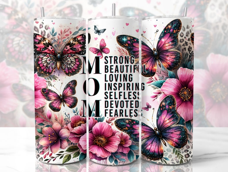 May include: A white tumbler with a floral design and butterflies. The tumbler has the word "MOM" on the left side and the words "STRONG, BEAUTIFUL, LOVING, INSPIRING, SELFLESS, DEVOTED, FEARLESS" on the right side.