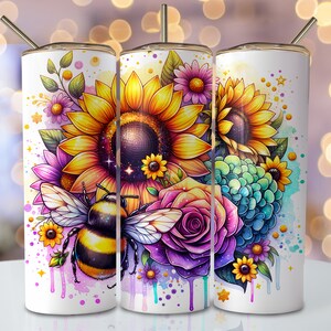 Pode incluir: Um copo branco com um design floral colorido que inclui girassóis, uma rosa e uma abelha. O design inclui gotas e respingos de aquarela.