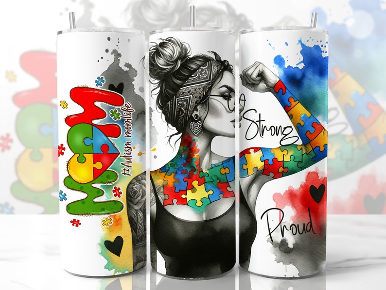 May include: A white tumbler with a watercolor design featuring a woman with a puzzle piece tattoo and the words "Strong" and "Proud". The tumbler also features the words "Mom" and "#Autism Momlife" in a colorful puzzle piece design.