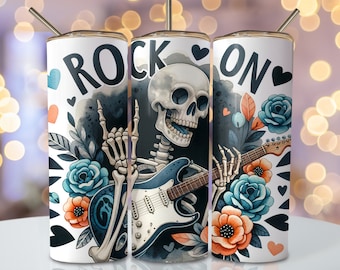 May include: A white tumbler with a skeleton playing a blue electric guitar with the words "Rock On" and hearts around the image. The skeleton is wearing a black bandana and has a skull with a toothy grin. The background is a watercolor wash of black and blue with floral accents.