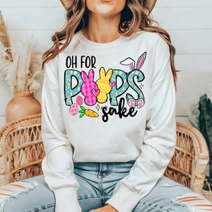 May include: White sweatshirt with a graphic design of a bunny with the text "Oh for Pups sake" in colorful letters.