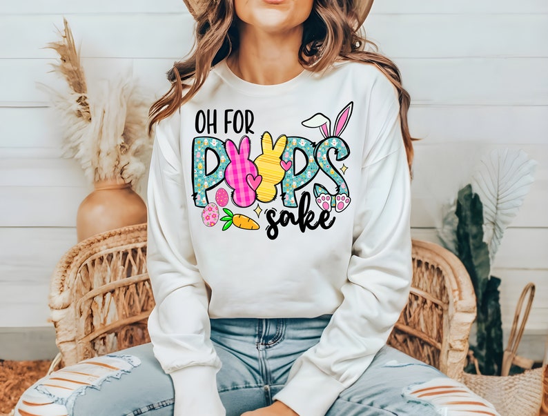 May include: White sweatshirt with a graphic design of a bunny with the text "Oh for Pups sake" in colorful letters.