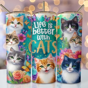 May include: Three stainless steel tumblers with colorful cat illustrations and floral designs. The middle tumbler features the text "Life is better with cats".