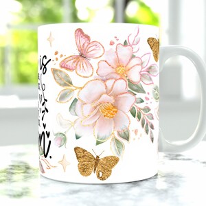 May include: White ceramic mug with a black inscription that reads "This is my happy place" and a floral design featuring pink flowers, green leaves, and gold butterflies.