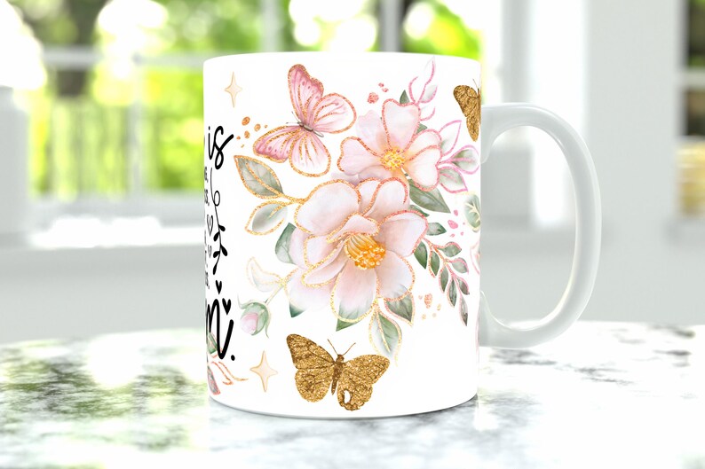 May include: White ceramic mug with a black inscription that reads "This is my happy place" and a floral design featuring pink flowers, green leaves, and gold butterflies.