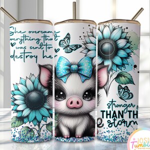 May include: A white tumbler with a blue and white sunflower design, a pig with a blue bow, and butterflies. The tumbler has the text "She overcame everything that was sent to destroy her" and "stronger than the storm".