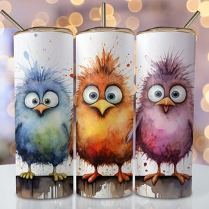 May include: Three stainless steel tumblers with colorful cartoon birds painted on them. The birds have large eyes and are painted in a watercolor style. The tumblers are on a white background.