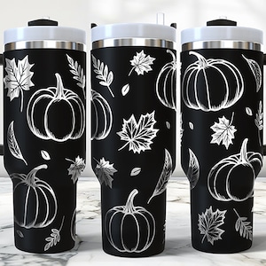 May include: Three black stainless steel travel mugs with a white pumpkin and leaf design. The mugs have a black handle and a black lid.