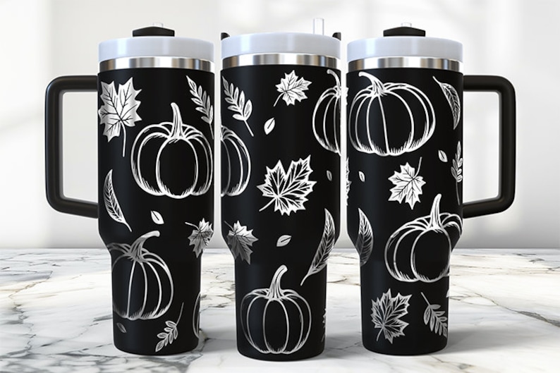 May include: Three black stainless steel travel mugs with a white pumpkin and leaf design. The mugs have a black handle and a black lid.