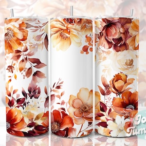 Puede incluir: Tres vasos de acero inoxidable con fondo blanco y un diseño floral en tonos naranja, amarillo y marrón. El diseño presenta flores y hojas de estilo acuarela.