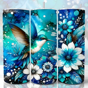 May include: A blue and white tumbler with a hummingbird and floral design. The hummingbird is flying with its wings spread. The flowers are in shades of blue and white.