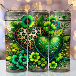 May include: A green and gold glitter heart with a leopard print heart behind it. The hearts are surrounded by green shamrock leaves and flowers on a wood background.