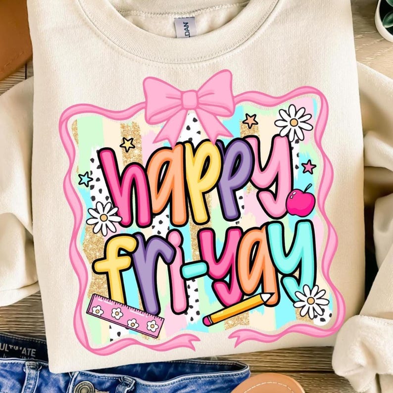 May include: Cream-colored sweatshirt with a colorful graphic that says "Happy Fri-Yay." The design includes a pink bow, stars, flowers, a ruler, a pencil, and a pink apple. The text is in various bright colors.