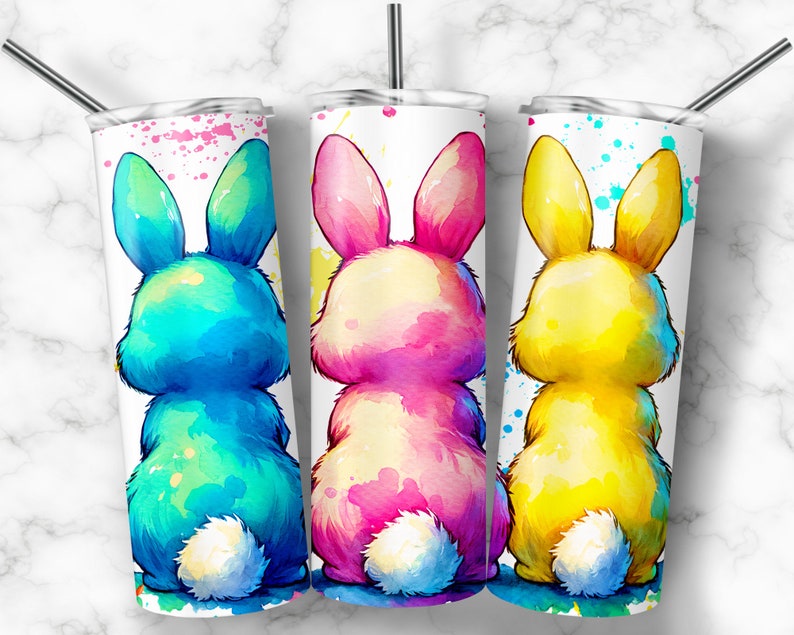 Op de afbeelding: Drie roestvrijstalen bekers met een witte achtergrond en aquarel konijnenontwerpen. De konijnen kijken weg van de kijker en zijn in tinten blauw, roze en geel.