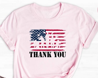 May include: Pink t-shirt with a distressed American flag graphic and the text "Thank You".