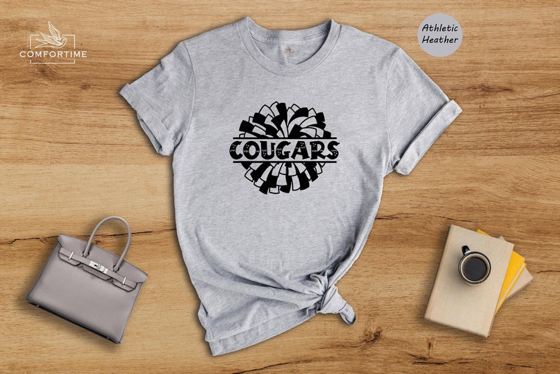 May include: Gray athletic heather t-shirt with a black and white pom-pom design and the word "COUGARS" in a black banner.