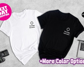 May include: Two t-shirts, one white and one black, with a simple logo design that says "Your logo goes here". The shirts are laid out on a gray surface with a laptop and camera in the background. The text "Next Day Shipping" and "Black" are visible in the image.