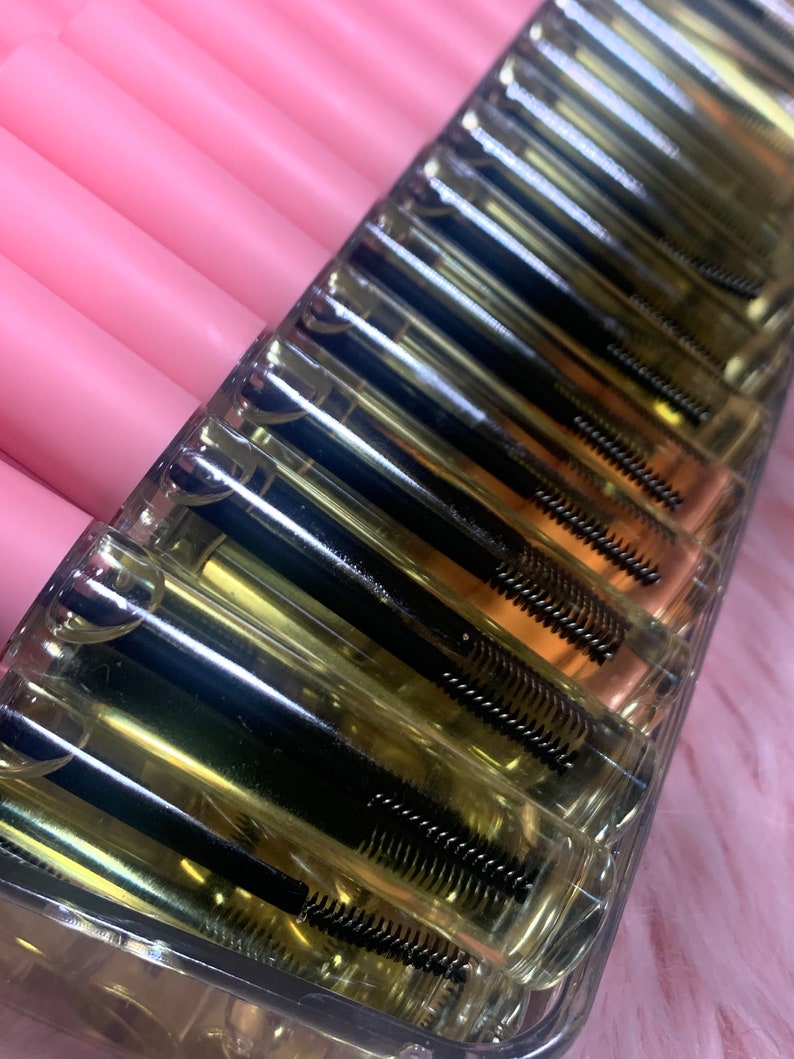 K&ouml;nnte beinhalten: Ein durchsichtiger Plastikbeh&auml;lter mit mehreren Reihen kleiner, durchsichtiger R&ouml;hrchen, die mit einer klaren Fl&uuml;ssigkeit und schwarzen Mascara-Wands gef&uuml;llt sind.