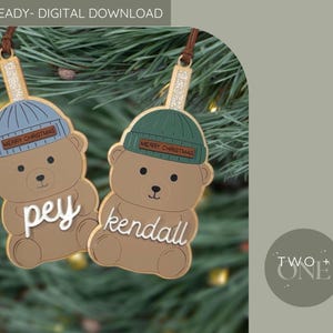 Peut inclure: Deux décorations de Noël en forme d'ours avec des noms personnalisés. Chaque ours porte un bonnet avec "MERRY CHRISTMAS" dessus. Les décorations sont marron avec des lettres blanches et sont suspendues à un cordon marron. Le texte "LASER READY- DIGITAL DOWNLOAD" est en haut.