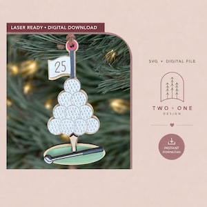 May include: A laser-cut wooden ornament featuring a stack of white golf balls forming a tree shape, topped with a flag labeled 25. A golf club rests horizontally on a green base at the bottom. The text LASER READY DIGITAL DOWNLOAD is visible.