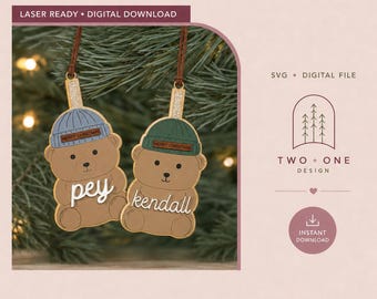 May include: Two bear-shaped ornaments with brown bodies, one wearing a blue beanie and the other a green beanie. Each beanie has a small brown tag reading MERRY CHRISTMAS. The names pey and kendall are written in white script across the bears.