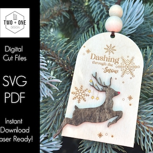 May include: A wooden Christmas bauble featuring a reindeer silhouette and the text "Dashing through the Snow". The bauble is decorated with snowflakes and stars.