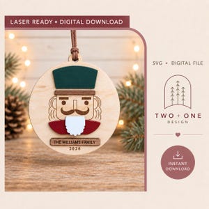 May include: A circular wooden ornament featuring a layered nutcracker design with a dark green hat, brown trim, red jacket, and white beard. A rectangular wooden plaque at the bottom is engraved with the text THE WILLIAMS FAMILY and 2026.