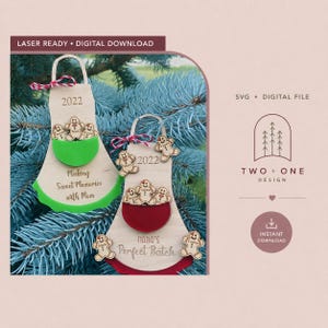 May include: Two wooden apron-shaped ornaments featuring the year 2022, gingerbread person cutouts with names, and text reading Making Sweet Memories with Mom and NANA'S Perfect Batch. The ornaments have green and red accents and red-white twine.