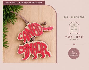 Pode incluir: Dois ornamentos de madeira cortados a laser com a palavra CANADA numa fonte vermelha estilizada, em forma de castor. Os ornamentos estão ligados por um cordão castanho fino. O texto inclui LASER READY, DIGITAL DOWNLOAD, SVG e TWO + ONE DESIGN.