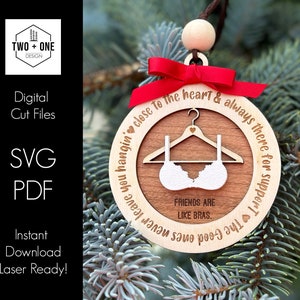 May include: A wooden Christmas bauble with a red ribbon and the text "To the heart & always there for support!"  The bauble also features a bra and the text "Friends are like bras."