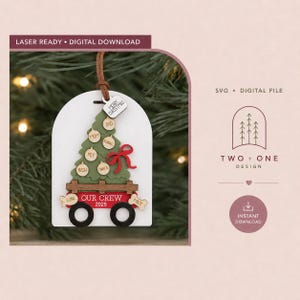 May include: A laser-ready digital download file for a Christmas ornament featuring a green tree on a red wagon with black wheels. The design includes text reading "OUR CREW 2025" and "MERRY CHRISTMAS" with space for names on small circular ornaments.