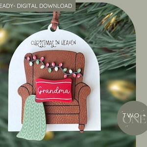 May include: A Christmas decoration depicting a brown armchair with a red cushion reading "Grandma." The ornament includes a green blanket, fairy lights, and the text "Christmas in Heaven." It is a digital download.