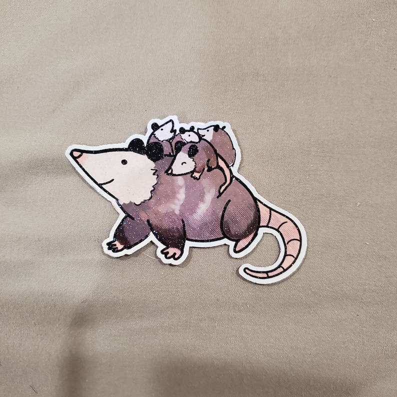 May include: A grey and white opossum with a pink nose and black eyes is carrying three smaller opossums on its back. The opossums are all facing forward and have black eyes and pink noses. The opossum is standing on a light brown surface.