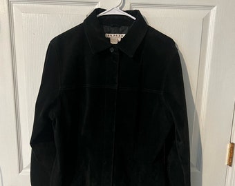 May include: A black suede jacket with a button-up front and long sleeves. The jacket has a small label on the left side of the chest that says "AMI".