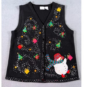 Op de afbeelding: Zwarte kersttrui vest met een V-hals en knoopsluiting. Het vest heeft een sneeuwpop, kerstbomen, cadeaus, sterren en sprankelende accenten. De sneeuwpop draagt een rode hoed, sjaal en laarzen. Het vest is versierd met kleurrijk borduurwerk.