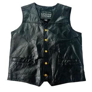 May include: Black leather vest with a patchwork design, featuring a V-neck and gold-colored buttons. The vest has two front pockets and a label that reads "GENUINE LEATHER".