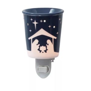 Può includere: Un riscaldatore di cera a spina in ceramica blu e bianca con un design di scena della natività. Il riscaldatore presenta una stella e una mangiatoia con la sacra famiglia all'interno.
