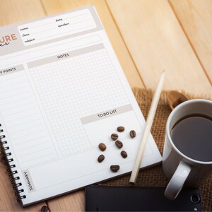 May include: A white spiral bound notebook with the words "LECTURE notes" printed on the cover. The notebook has sections for topic, key points, notes, to-do list, and summary. A pencil, a cup of coffee, and coffee beans are on a wooden surface next to the notebook.