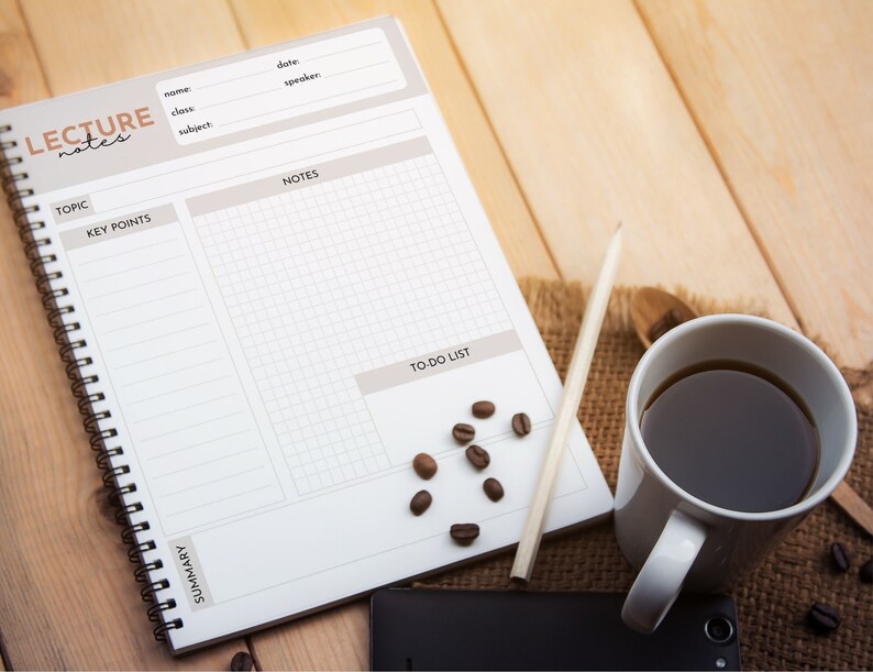 May include: A white spiral bound notebook with the words "LECTURE notes" printed on the cover. The notebook has sections for topic, key points, notes, to-do list, and summary. A pencil, a cup of coffee, and coffee beans are on a wooden surface next to the notebook.