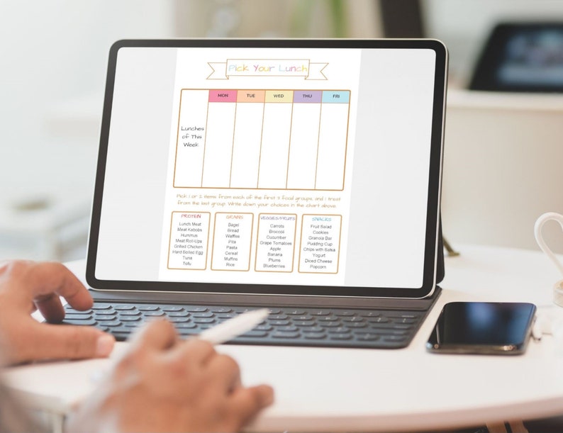 May include: A digital planner on a tablet screen with a colorful title "Pick Your Lunch". The planner is divided into days of the week and includes sections for protein, grains, fruits, and snacks.